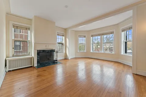 an empty room with windows fireplace and wooden floor