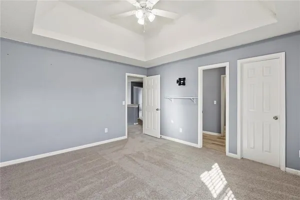 a view of a livingroom with wooden floor a ceiling fan and staircase