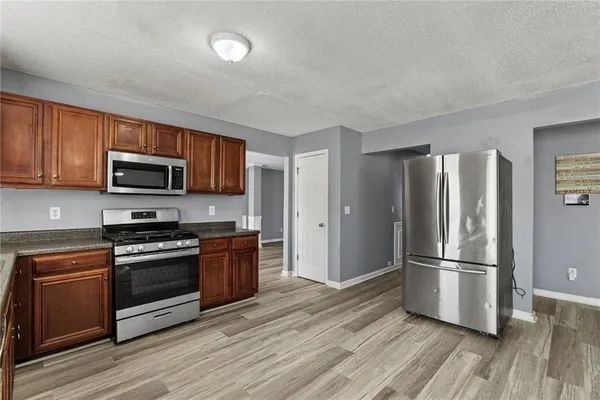 a kitchen with stainless steel appliances granite countertop a stove a sink dishwasher and a microwave oven with wooden floor