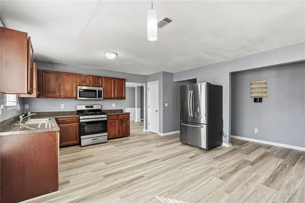 a kitchen with stainless steel appliances granite countertop a sink dishwasher stove and wooden cabinets