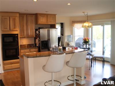 5219 Springmill Road Whitehall, PA 18052 - Photo 13 of 40 a kitchen with stainless steel appliances granite countertop a refrigerator a stove a sink dishwasher and white cabinets with wooden floor