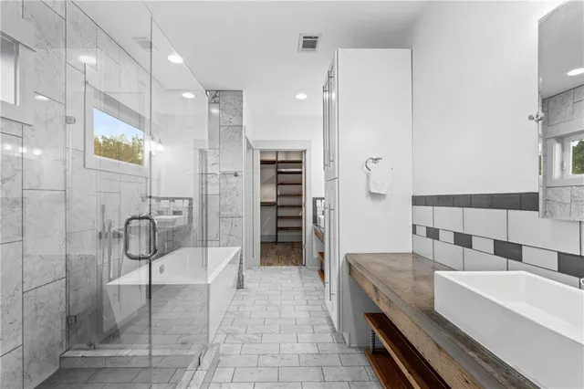 a bathroom with a tub a mirror and a shower