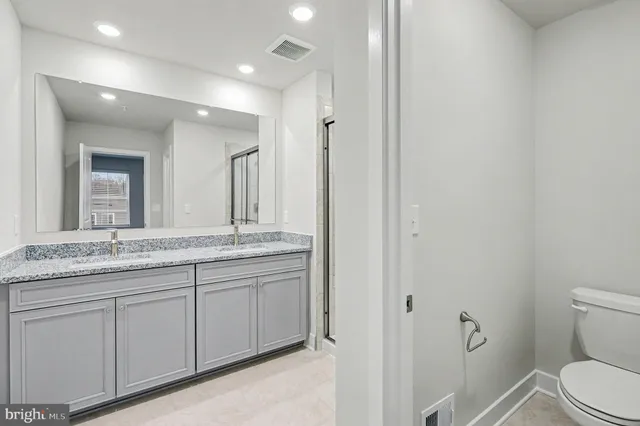 a bathroom with a granite countertop sink a toilet and a mirror
