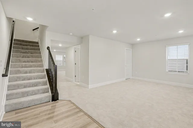 a view of an empty room with stairs and a ceiling fan