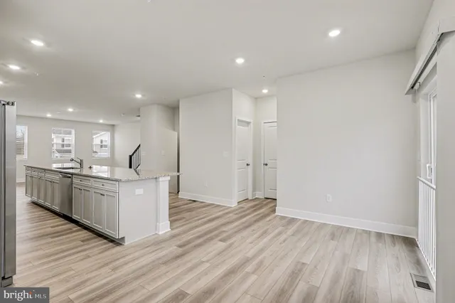 a kitchen with stainless steel appliances kitchen island wooden floors and white cabinets