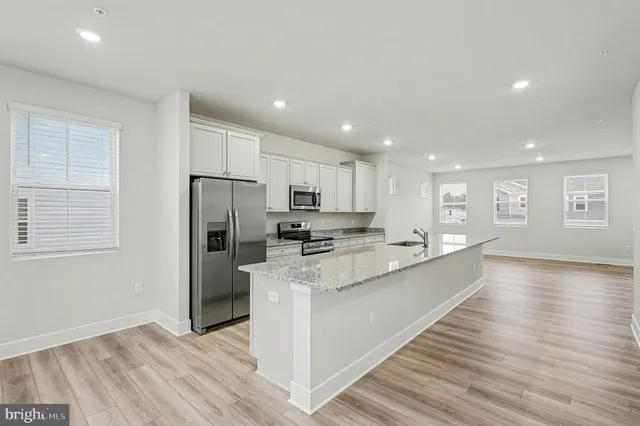 a large kitchen with stainless steel appliances kitchen island a large counter top and a wooden floors