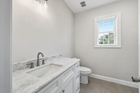 a bathroom with a granite countertop toilet a sink and a mirror