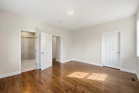 a view of an empty room with wooden floor and window