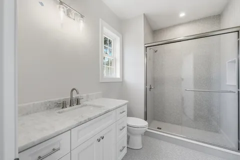 a bathroom with a granite countertop sink toilet and shower