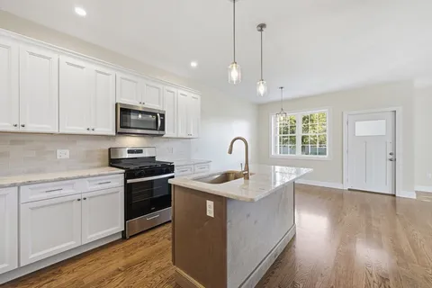 a kitchen with stainless steel appliances granite countertop a sink stove and wooden floor