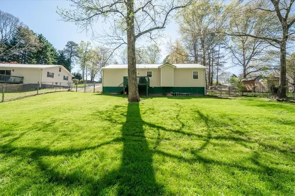a view of a white house with a big yard and large tree