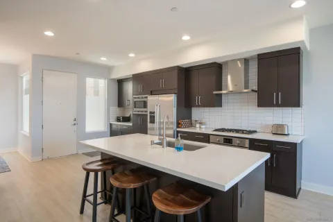 a kitchen with a table a refrigerator a cabinets and stools