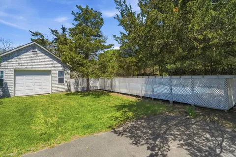 a view of a backyard with large trees and wooden fence