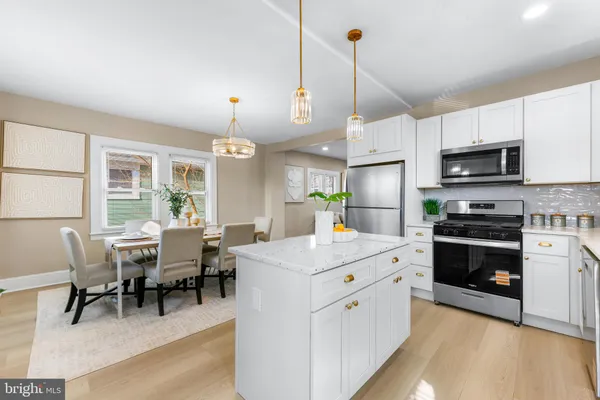 a kitchen with kitchen island white cabinets and stainless steel appliances