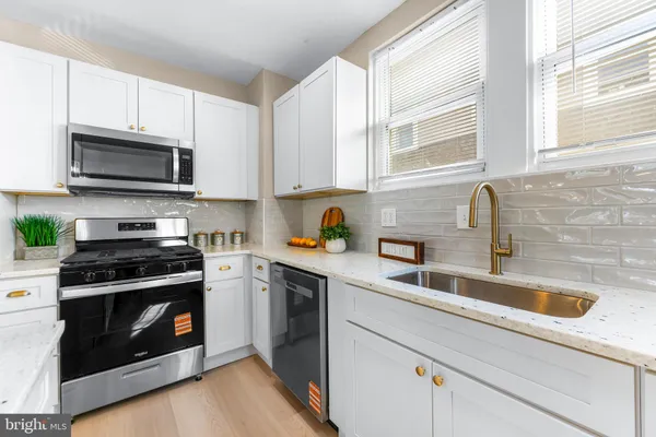 a kitchen with cabinets stainless steel appliances a sink and a window