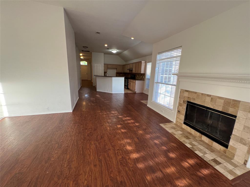 334 Touchdown Drive Irving, TX 75063 - Photo 15 of 32 Spacious living area featuring wood-finish flooring, a tiled fireplace with a mantel, and a window with blinds