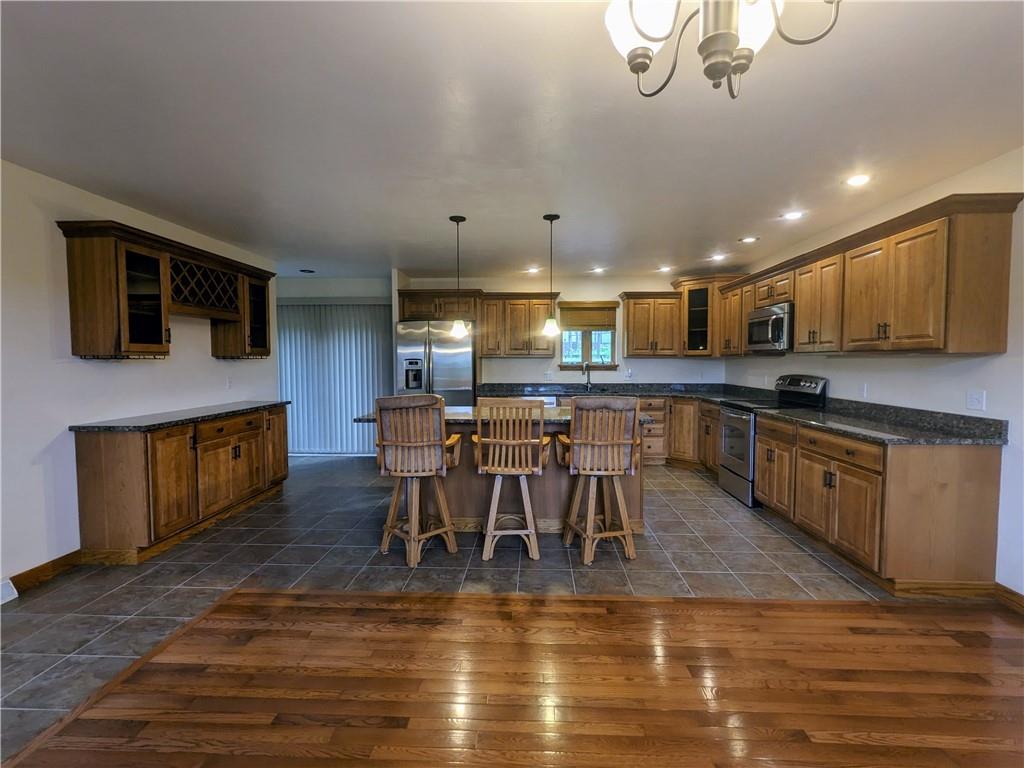 350 American Legion Road Latrobe, PA 15650 - Photo 9 of 45 a kitchen with stainless steel appliances granite countertop a stove top oven a sink a dining table and chairs with wooden floor