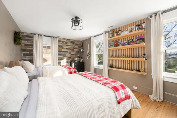 a bedroom with a bed a dresser and a large window
