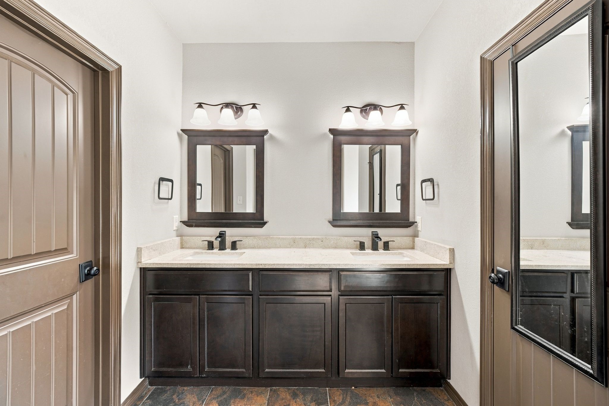 7049 Pine Shadows Road Cleveland, TX 77328 - Photo 17 of 49 Elegant bathroom featuring a double vanity with rich dark wood cabinets, framed mirrors, and stylish lighting.