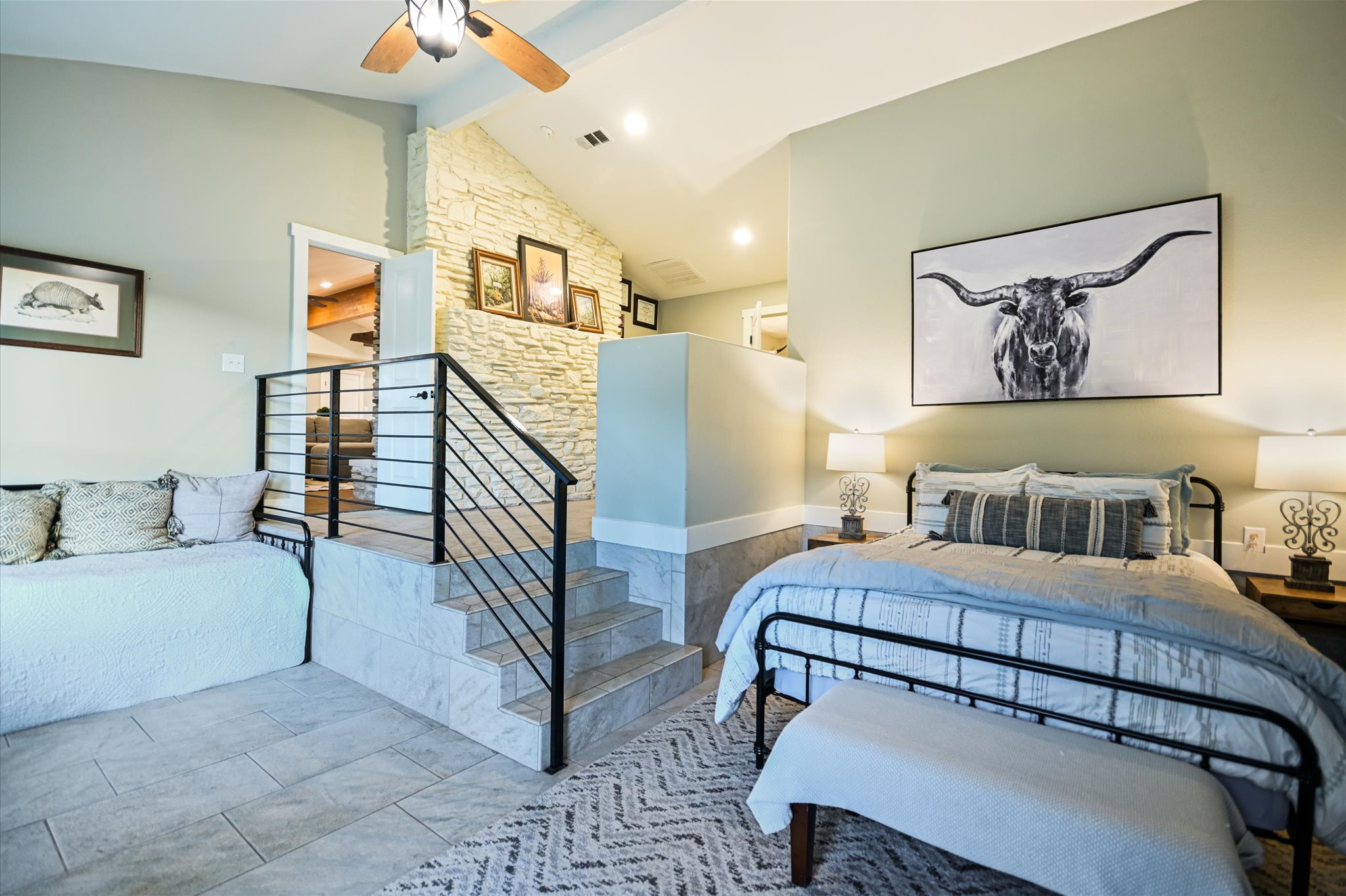 2411 Spoke Hollow Road Wimberley, TX 78676 - Photo 30 of 37 Natural light illuminates the bedroom with high ceilings and a distinctive stone accent wall.