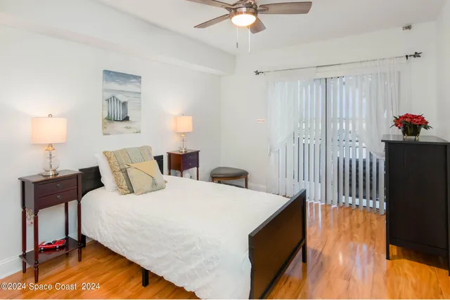 a bedroom with a bed and a lamp on table and wooden floor