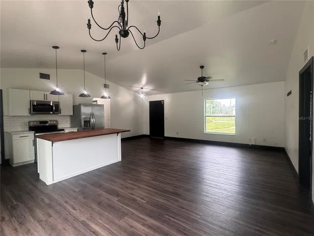 a kitchen with stainless steel appliances granite countertop a sink a stove a refrigerator and island with wooden floor