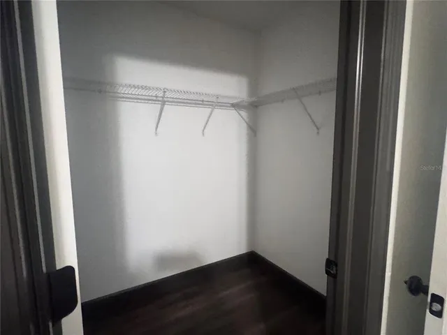 an empty room with wooden floor and a ceiling fan