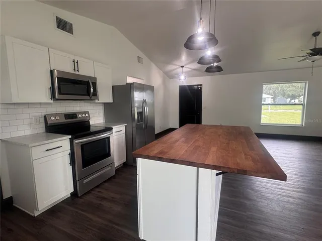 a kitchen with stainless steel appliances kitchen island granite countertop a stove a refrigerator and a microwave