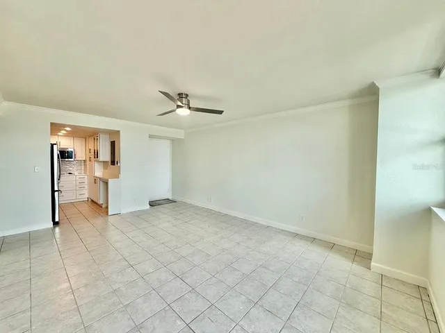 an empty room with chandelier fan and windows