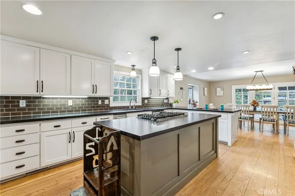 a kitchen with granite countertop a stove a sink a dining table and chairs with wooden floor