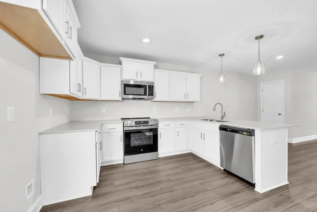 a kitchen with stainless steel appliances granite countertop a stove top oven a sink a microwave and wooden floors