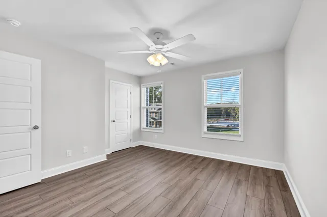 a view of an empty room with wooden floor and a window