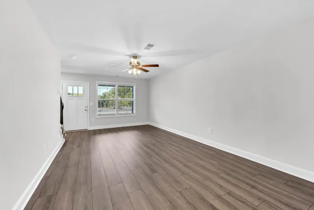 an empty room with wooden floor and windows