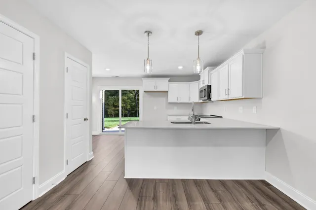 a large kitchen with stainless steel appliances granite countertop a sink a stove and a wooden floors