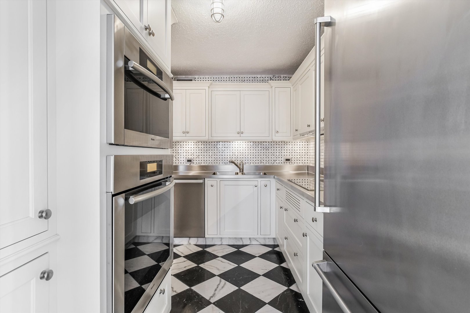 1450 North Astor Street, Unit 15AB Chicago, IL 60610 - Photo 8 of 23 a kitchen with white cabinets and appliances