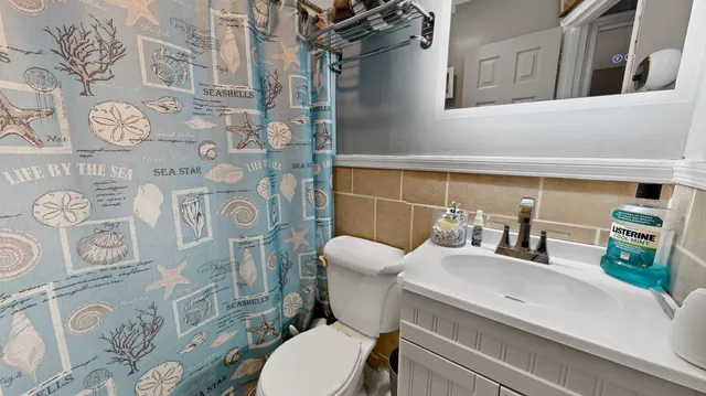 a bathroom with a toilet sink and shower curtain