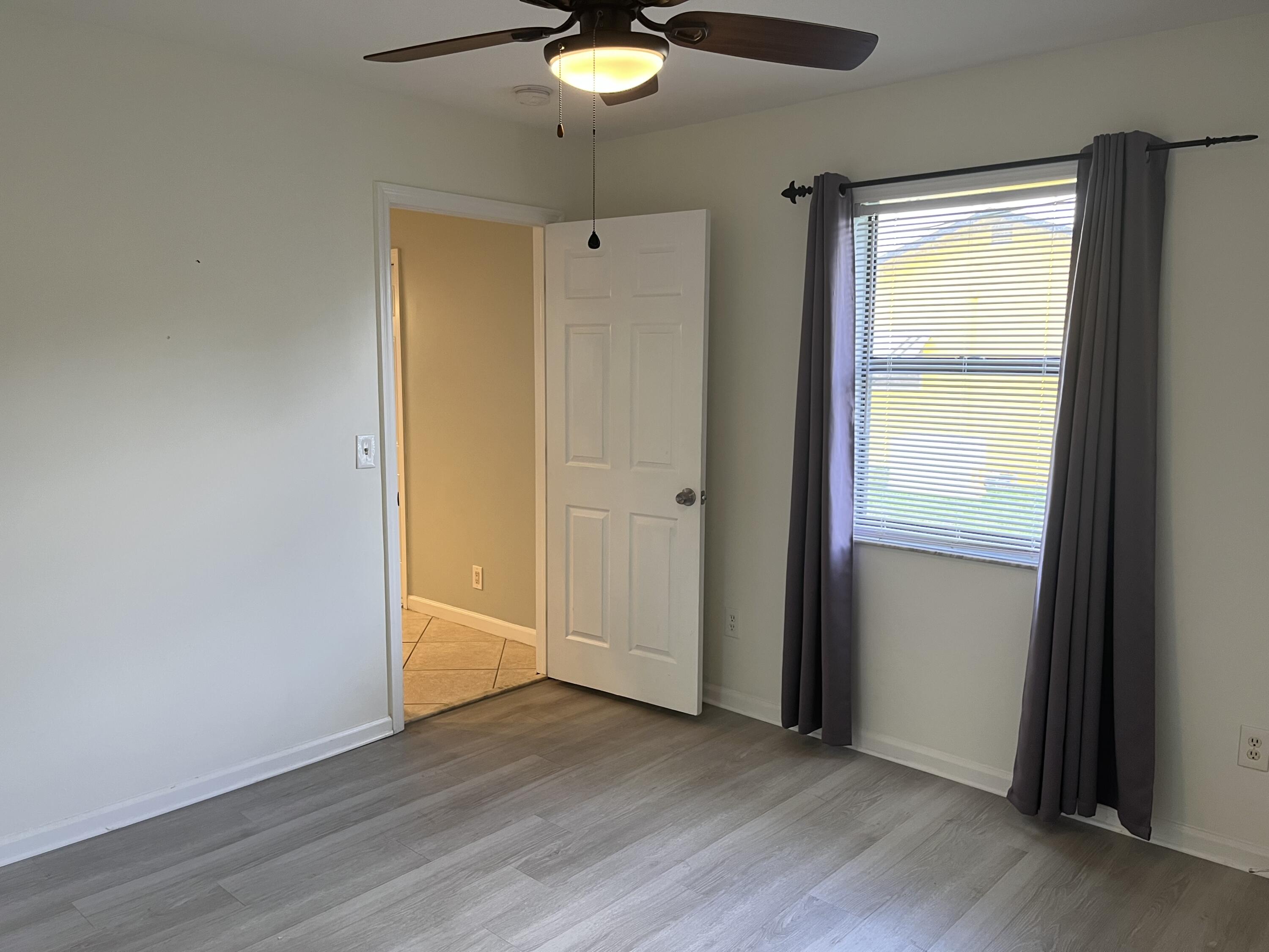 491 Southwest Curtis Street Port St. Lucie, FL 34983 - Photo 4 of 8 an empty room with wooden floor and windows