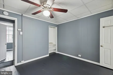 an empty room with wooden floor fan and windows