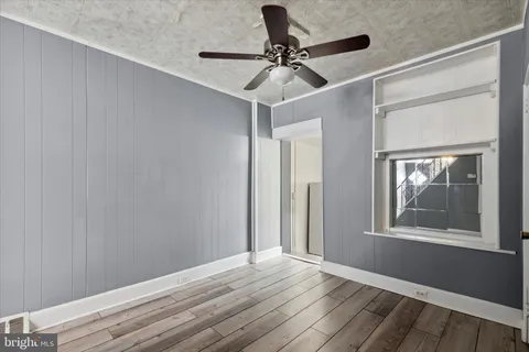 a view of an empty room with a window and wooden floor