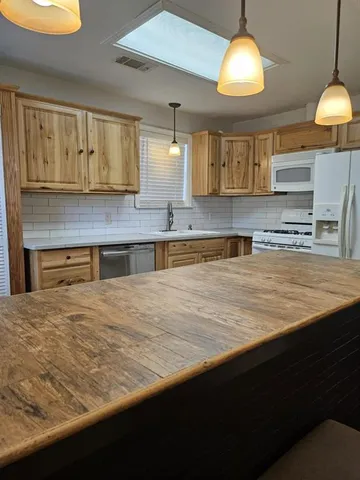 a kitchen with stainless steel appliances granite countertop a sink a stove and a wooden cabinets
