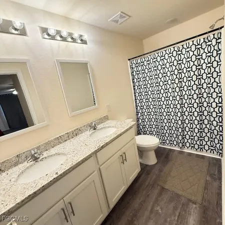 a bathroom with a granite countertop toilet a sink and a mirror