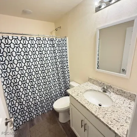 a bathroom with a granite countertop sink toilet and mirror
