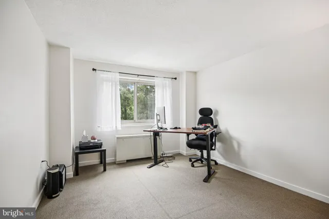 a view of a workspace with furniture and a window