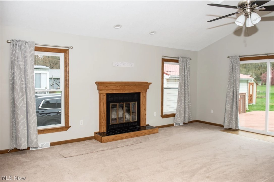 1721 State Road Northwest Warren, OH 44481 - Photo 15 of 37 Unfurnished living room featuring carpet flooring, a tile fireplace, ceiling fan, and lofted ceiling