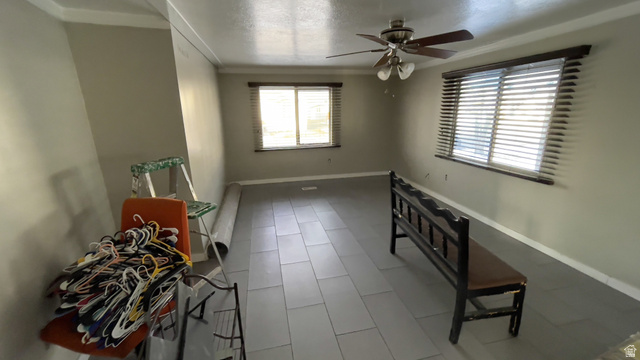 2491 Highway 89, Unit 114 Pleasant View, UT 84404 - Photo 3 of 18 Spare room featuring ornamental molding, a ceiling fan, a textured ceiling, and tile patterned floors