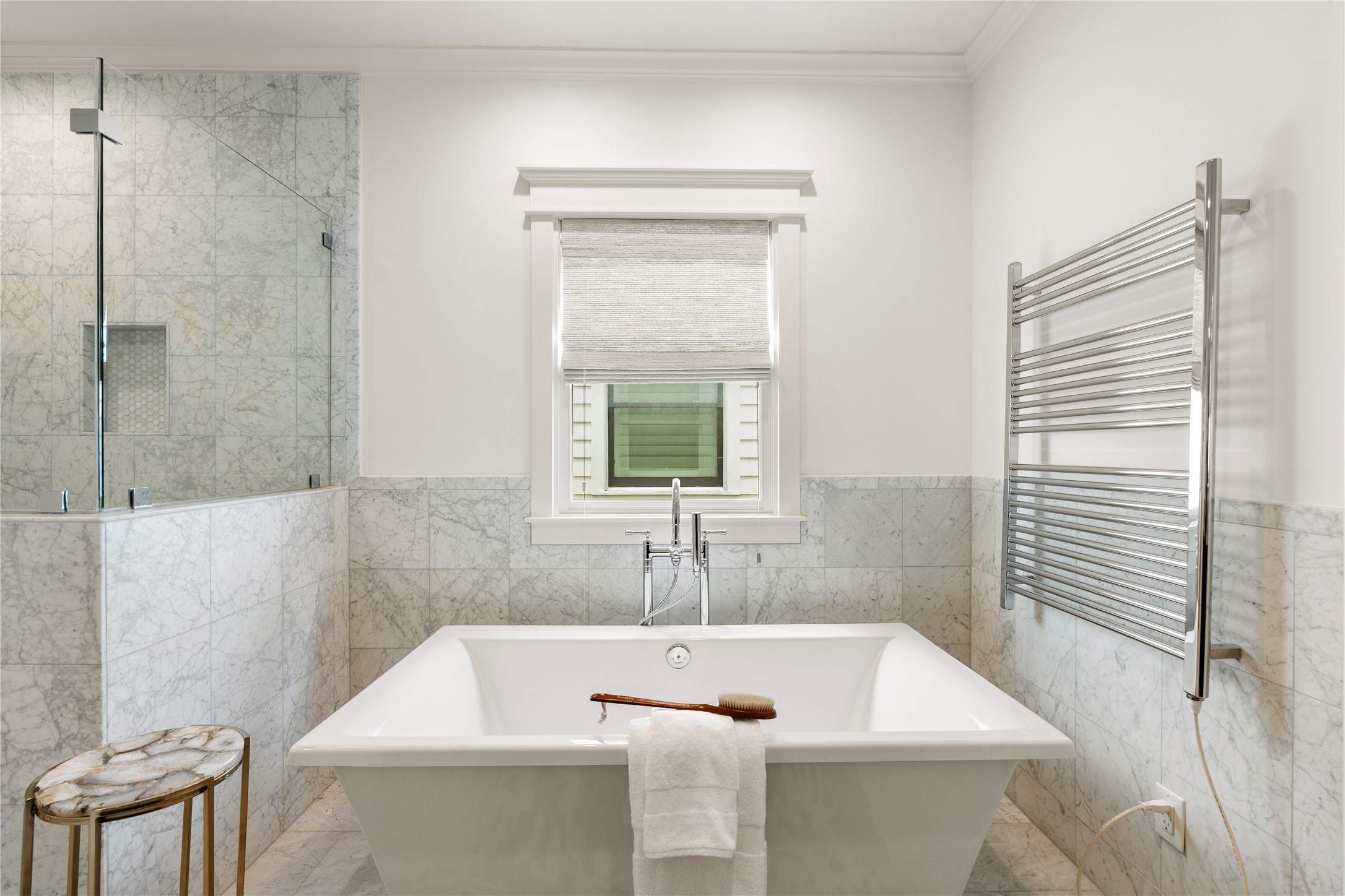 925 Tulane Street, Unit A Houston, TX 77008 - Photo 40 of 49 The freestanding soaking tub is positioned alongside a window and a large wall-mounted towel warmer.