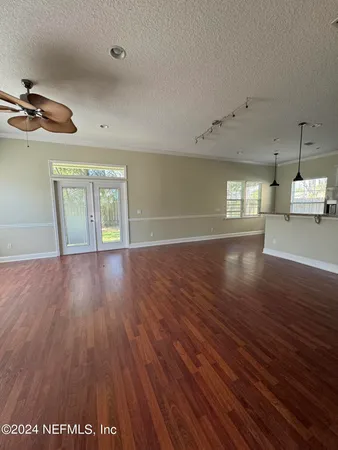 an empty room with wooden floor fireplace and windows