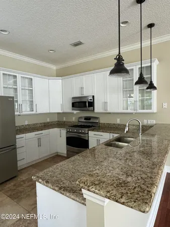 an empty room with wooden floor chandelier and windows