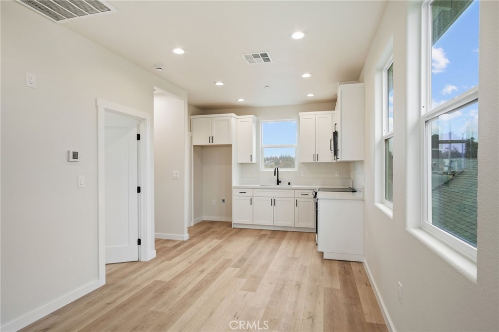 243 East 3rd Street Tracy, CA 95376 - Photo 17 of 29 a large kitchen with white cabinets and wooden floors