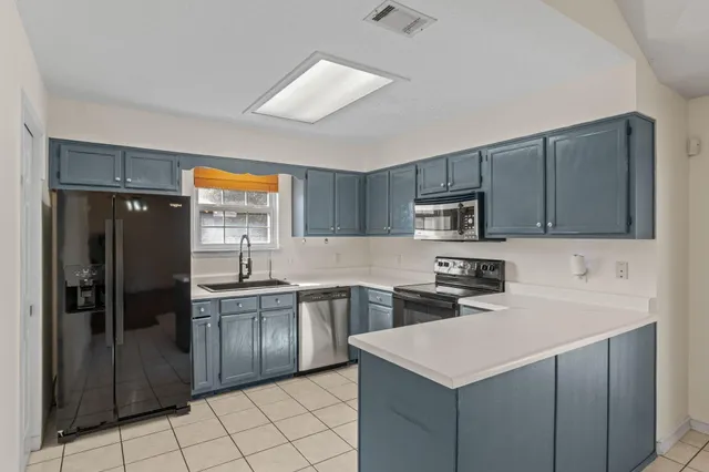 a kitchen with stainless steel appliances a sink stove refrigerator and cabinets